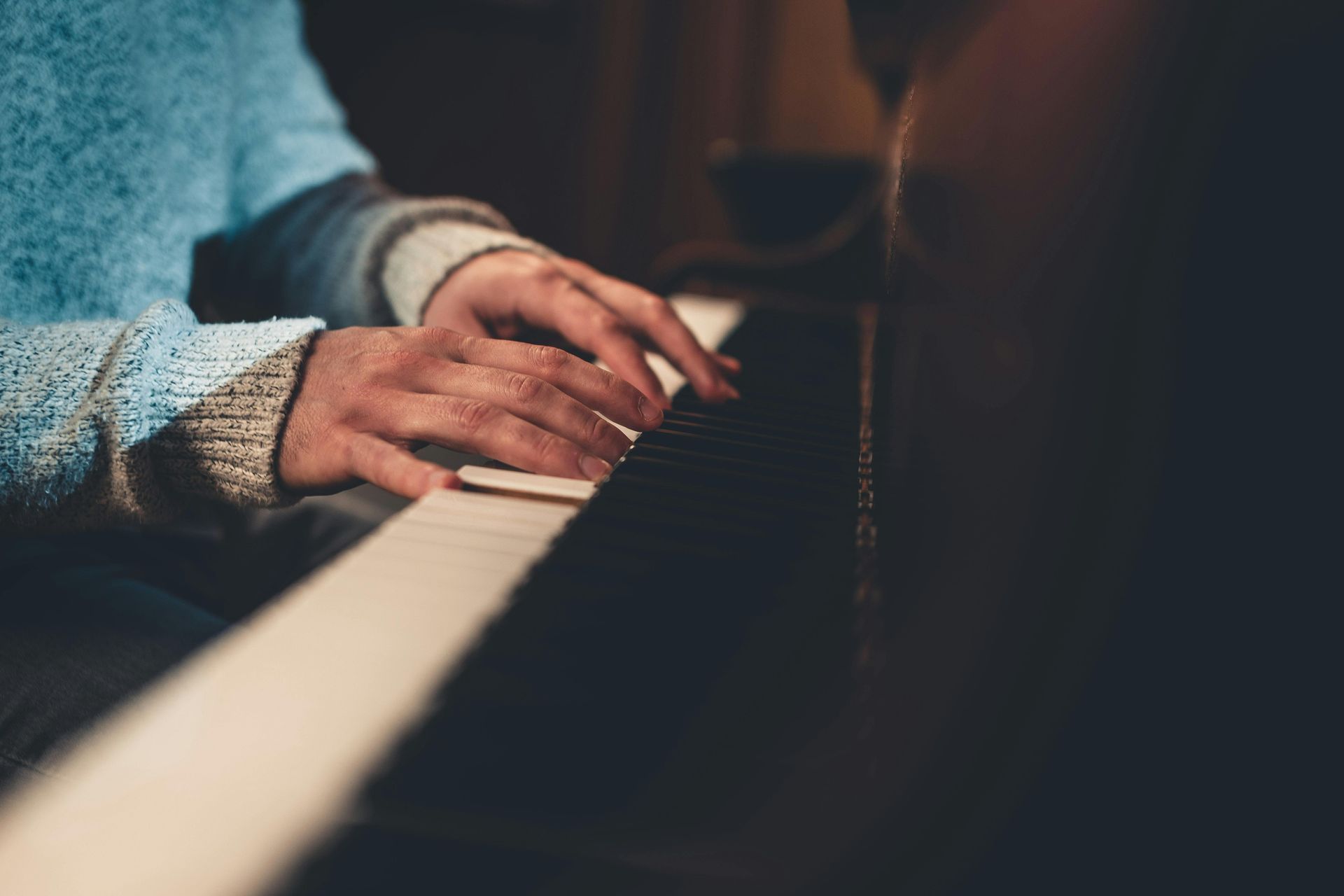 A person is playing a piano with their hands on the keyboard.