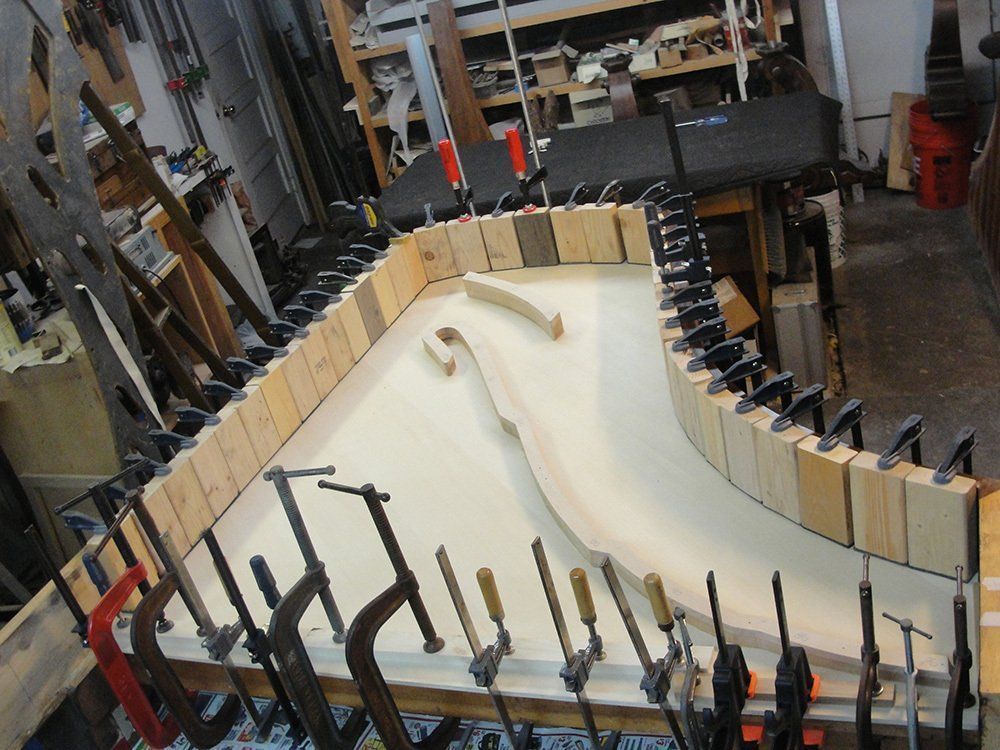 A large piece of wood is being glued together in a workshop