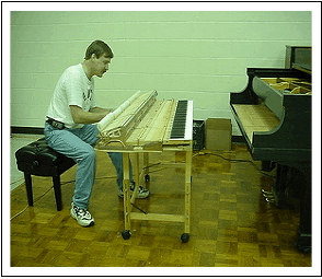 A man is sitting on a bench playing a piano
