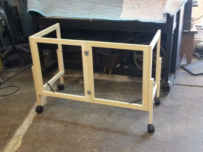 A white metal frame with wheels sits on a concrete floor