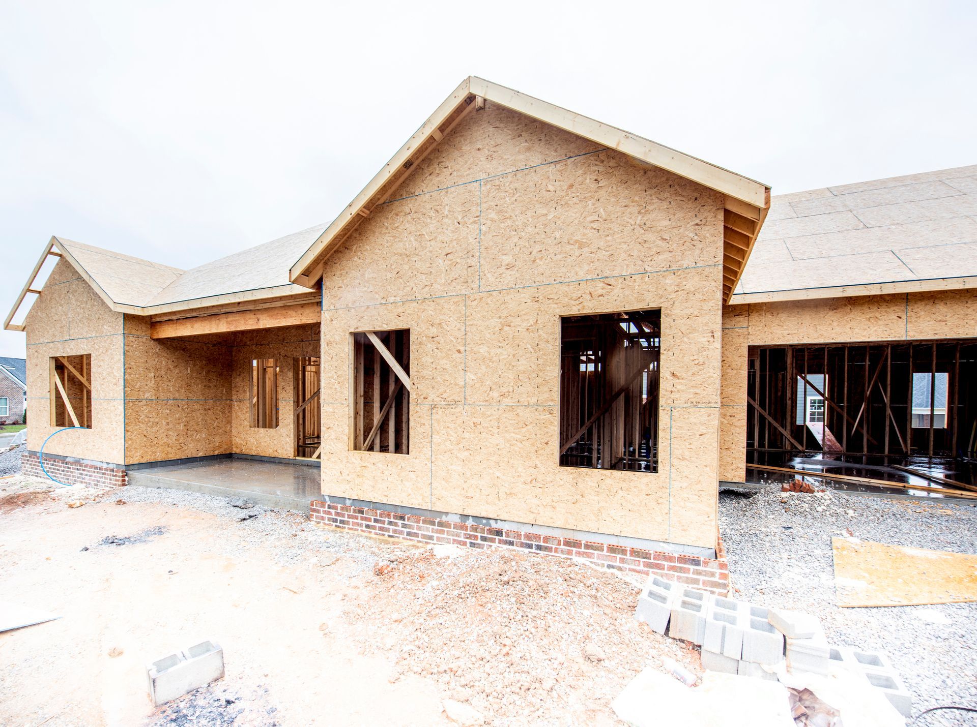 Exterior of a newly built brick house with unfinished windows and roof under construction