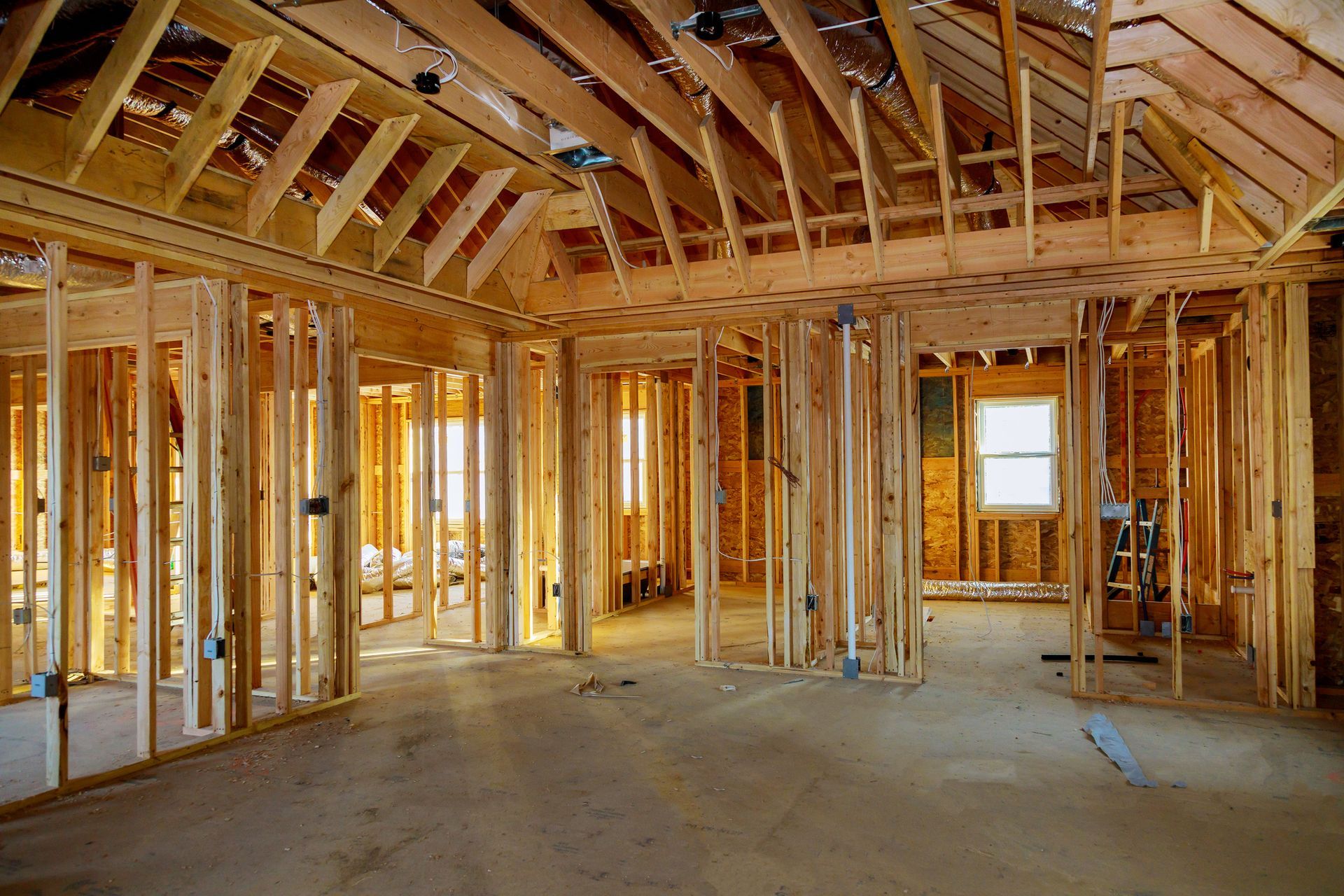Unfinished wooden house interior with exposed framing, beams, and window openings