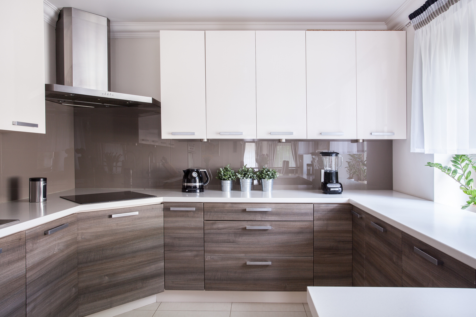 Modern kitchen with white upper cabinets, dark wood lower cabinets, and a gray tiled backsplash