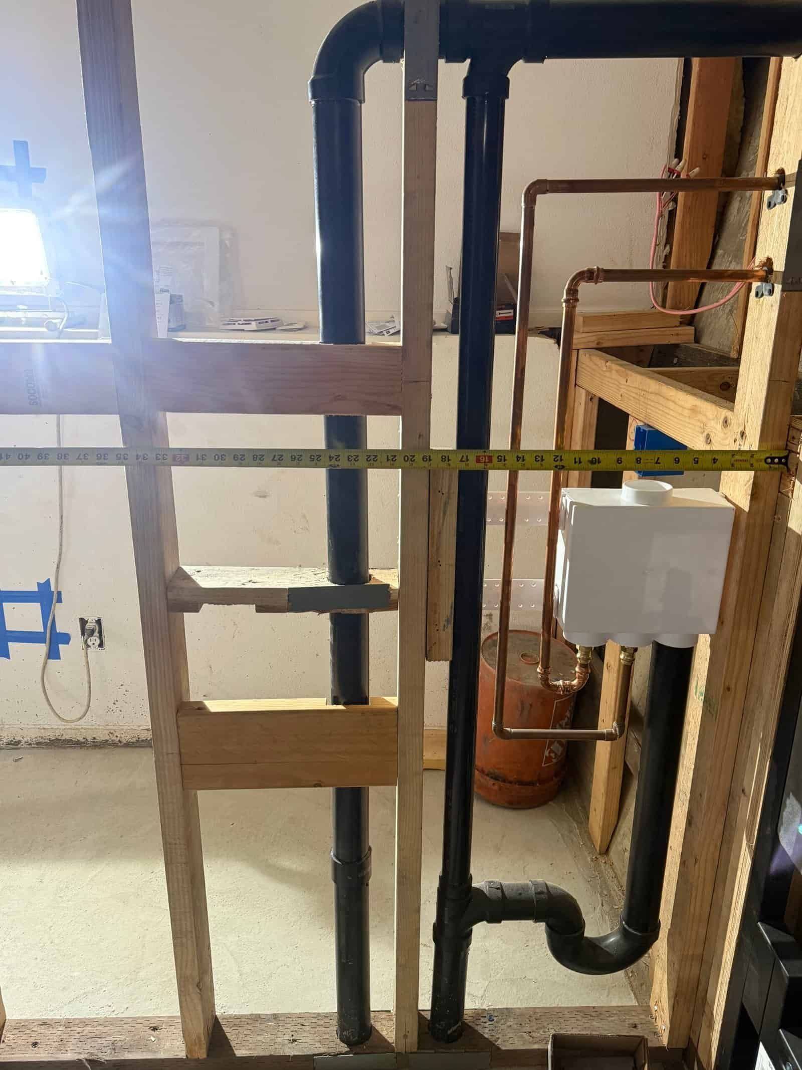 Basement utility area with black and copper pipes, a step ladder, and yellow tape across the room