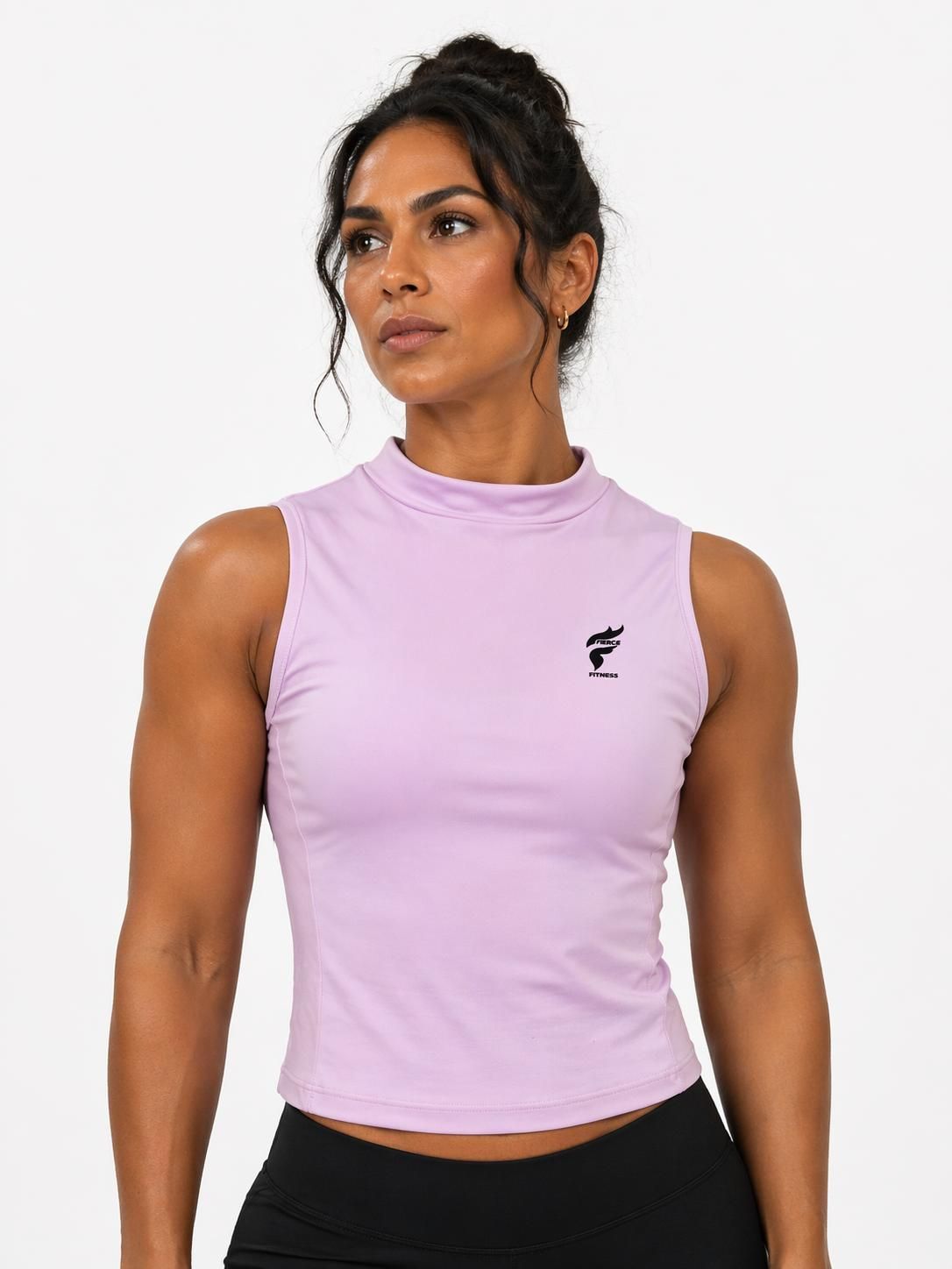 Woman in black sleeveless top standing against a white background, looking to the side.