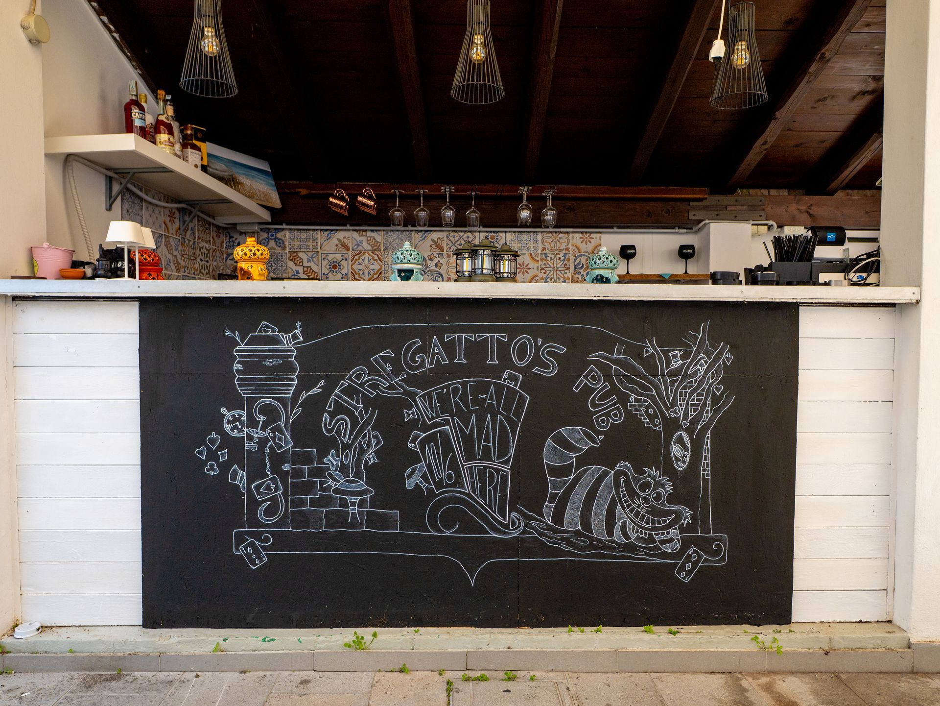 Bancone bar all'aperto con decorazioni bianche e nere. La parte anteriore è in lavagna e raffigura un giardino.