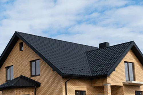 A brick house with a black roof and windows.