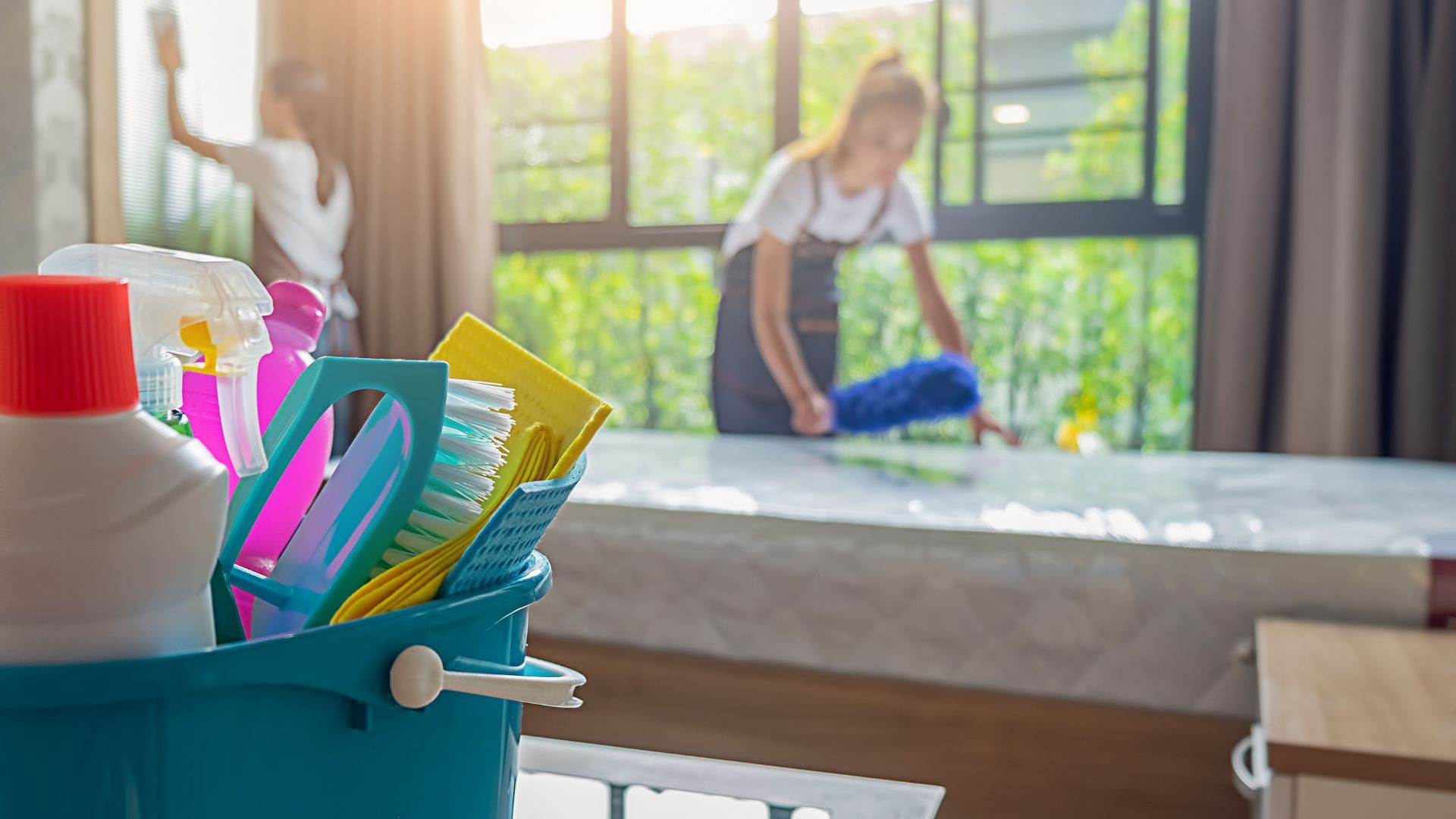 Two women are cleaning a room with cleaning supplies in Auburn Al