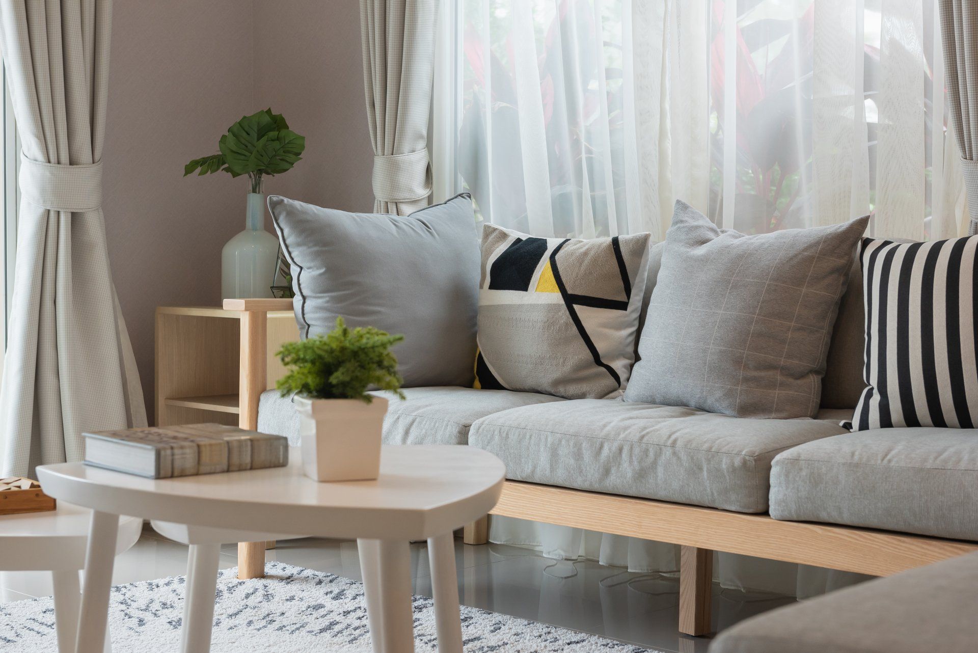 A clean living room with a couch , table , and potted plant.