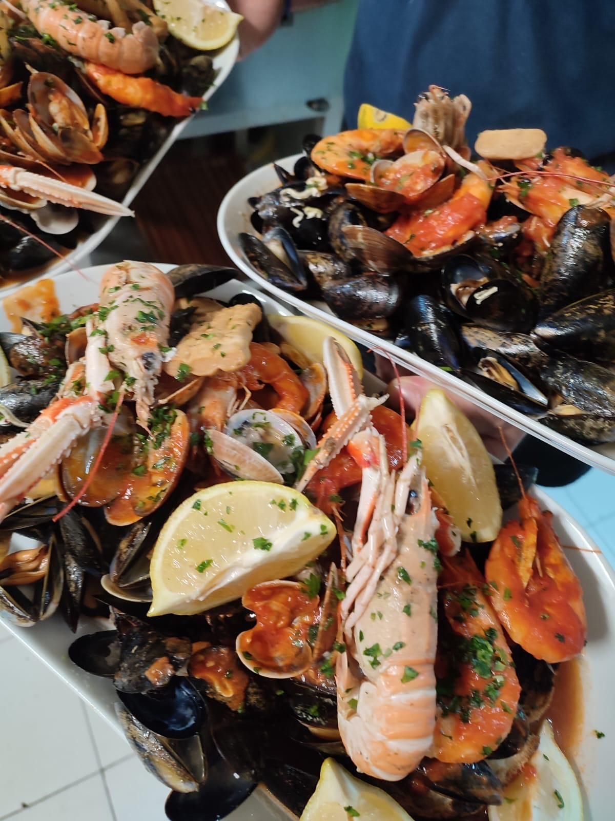 Prosciutto con pistacchi tritati su rucola, servito su un piatto bianco, con luci bokeh sullo sfondo.