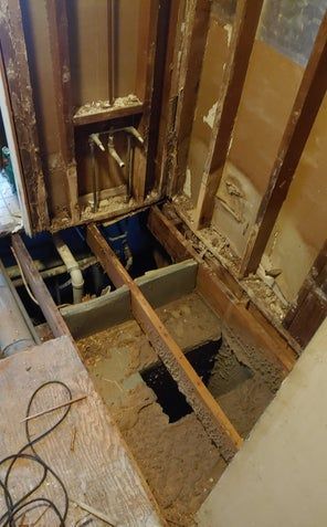 Bathroom renovation: exposed framing, pipes, and subfloor.