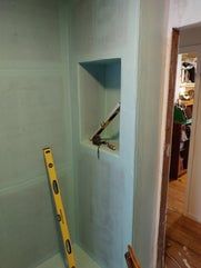 Bathroom wall with a niche, a level, and tools in progress. Light blue wall.