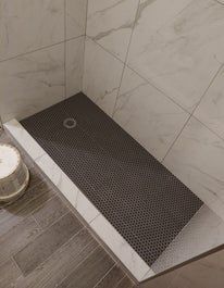 Shower stall with dark gray tiled floor, white tile trim, and marble wall tiles.
