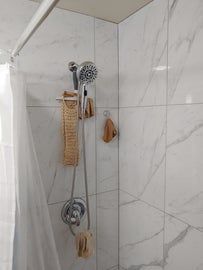 Shower with marble-like tile, shower head, and hanging washcloths.