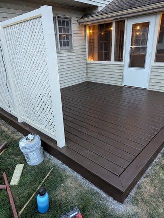 Brown deck with lattice screen, adjacent to a house. Construction materials visible.