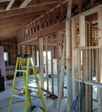 Interior construction view with exposed wooden framework and a yellow ladder.