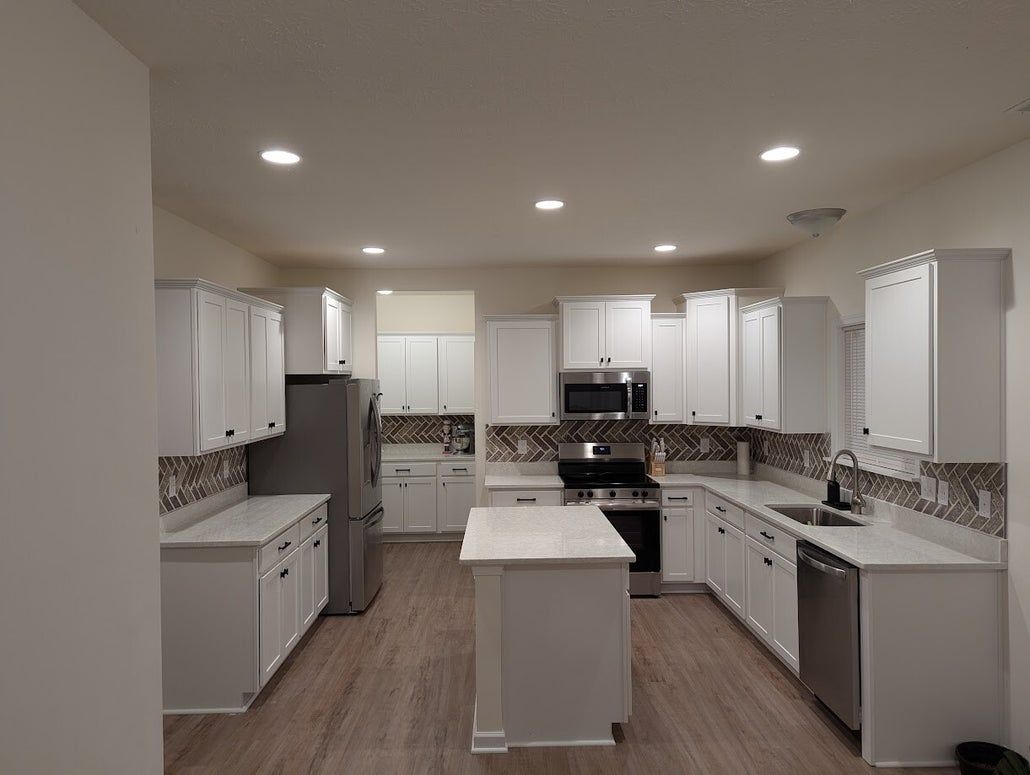 White kitchen with stainless steel appliances, white cabinets, and a center island.