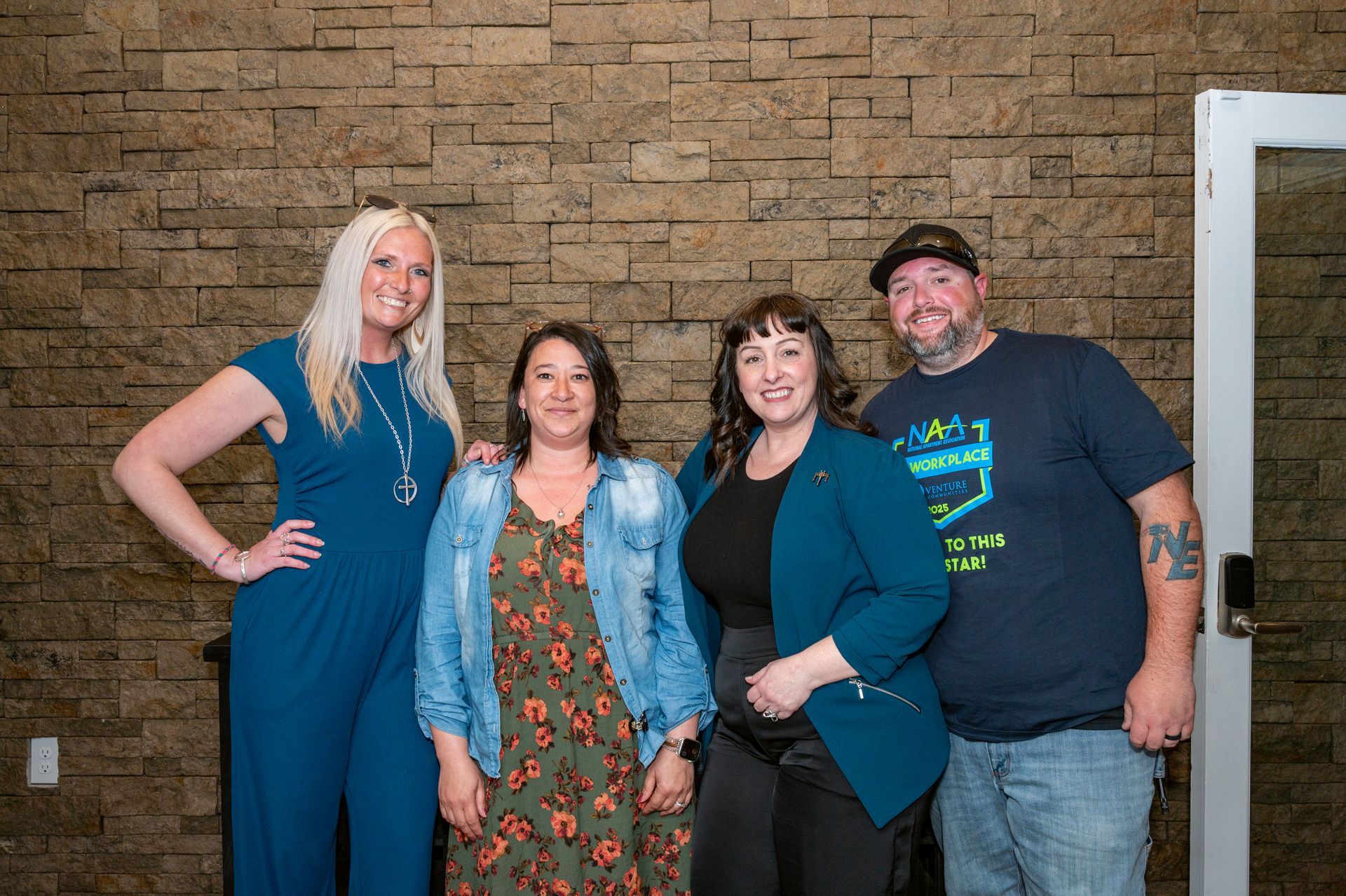 Four team members from Bridgewater and Knollwood posing for a group photo against a stone wall backdrop.