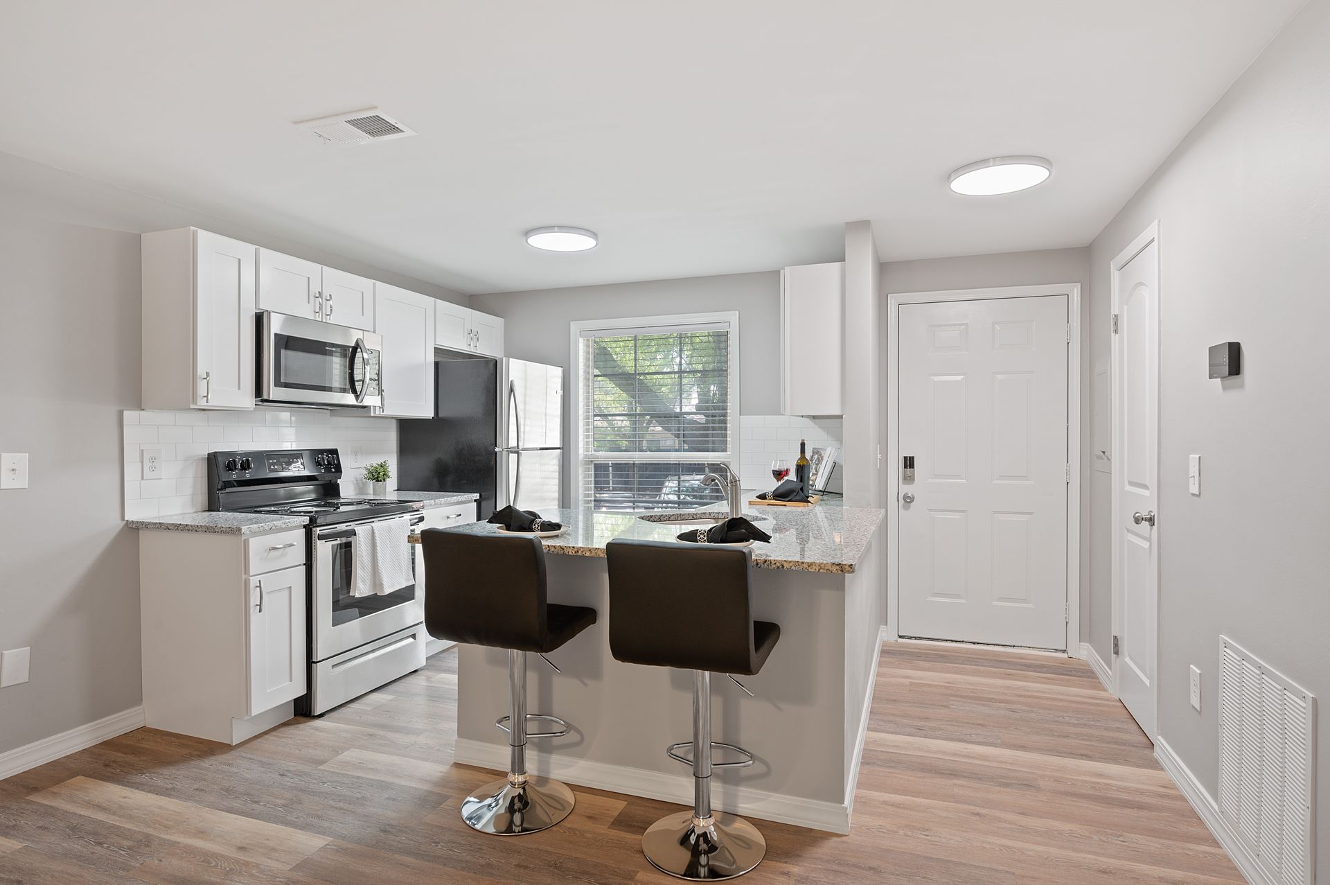 Modern kitchen with white cabinets, stainless steel appliances, and bar seating at Deerfield Berwick”