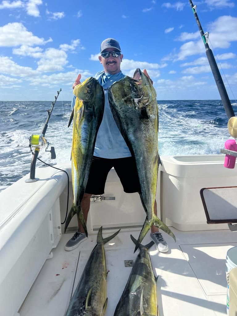 a man is holding two large fish on a boat in the ocean .