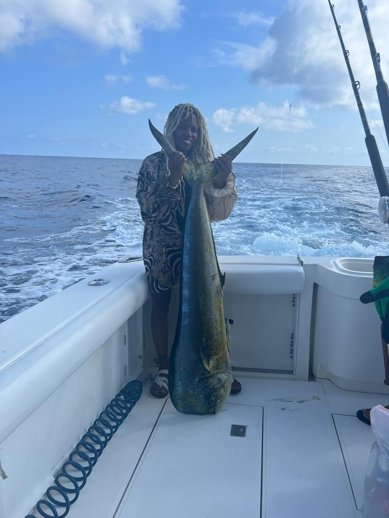 a man is holding a large fish on a boat in the ocean .