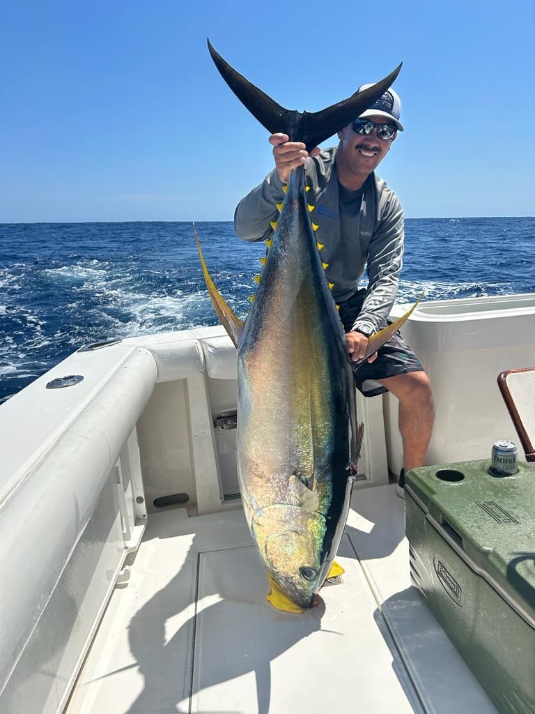 a man is holding a large fish on a boat in the ocean .