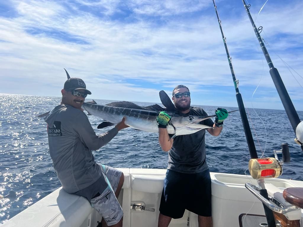 two men are standing on a boat holding a large fish .