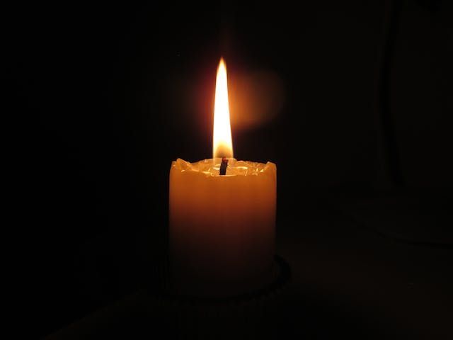 Lit candle in dark setting symbolizing remembrance and support from funeral homes in North Port, FL.