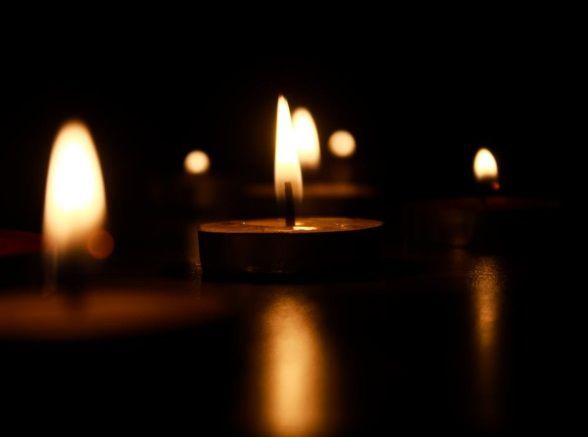 Small candles with soft glowing flames in a dark setting for North Port, FL cremation services.