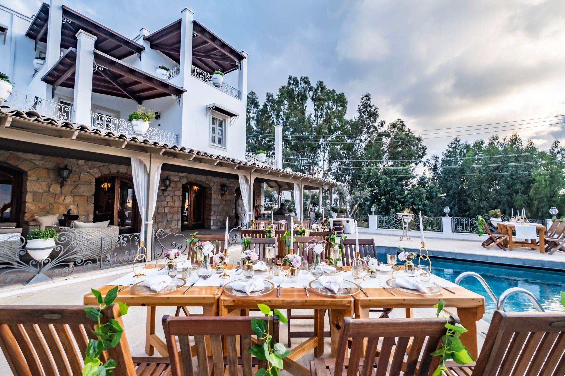 A large white house with a swimming pool and a table and chairs in front of it.