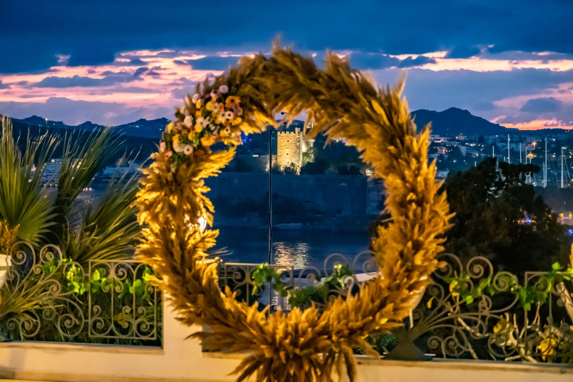 A large wreath of flowers is sitting on a balcony overlooking a city.