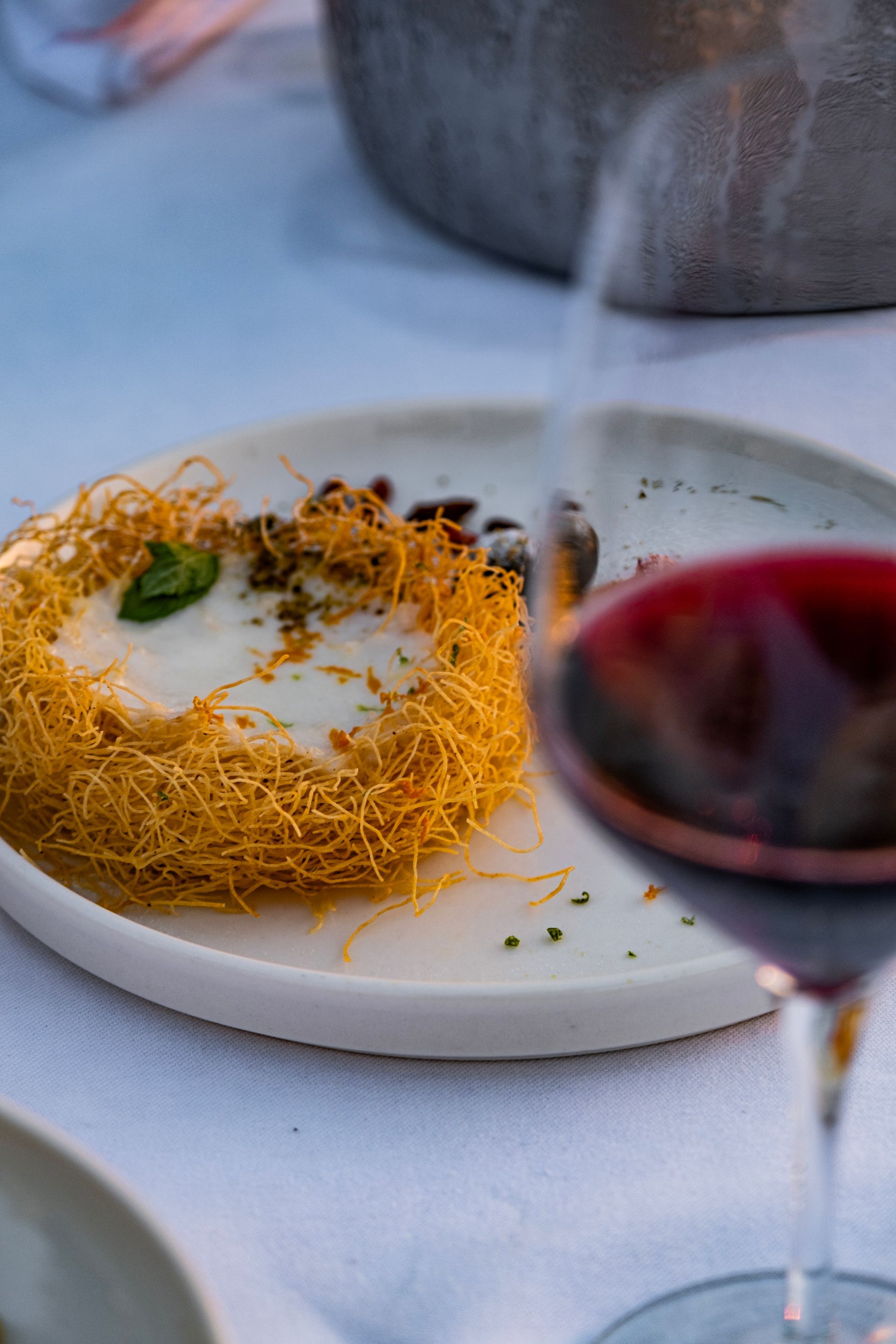 A plate of food and a glass of wine on a table.