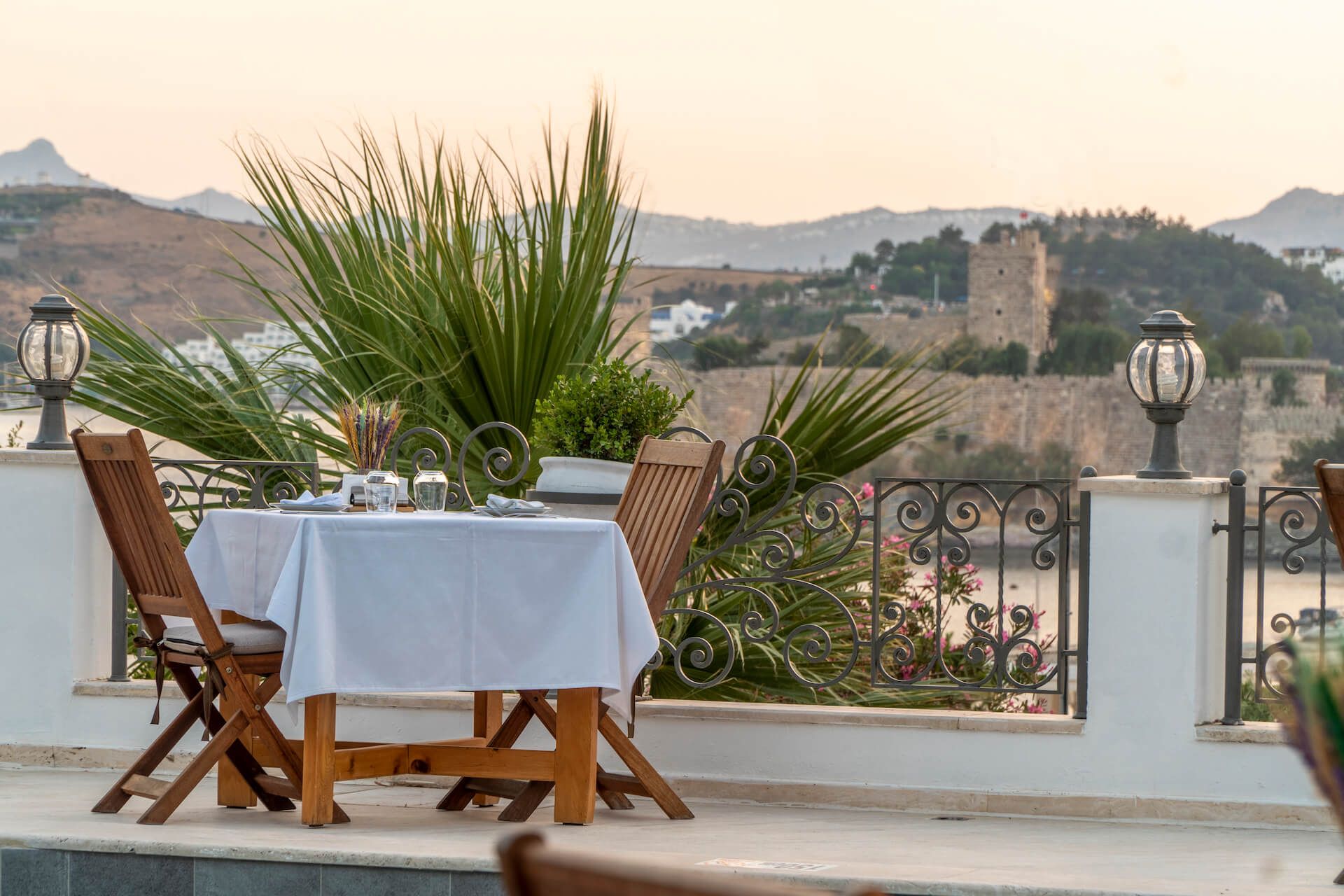 A table and chairs on a balcony with a view of a castle.