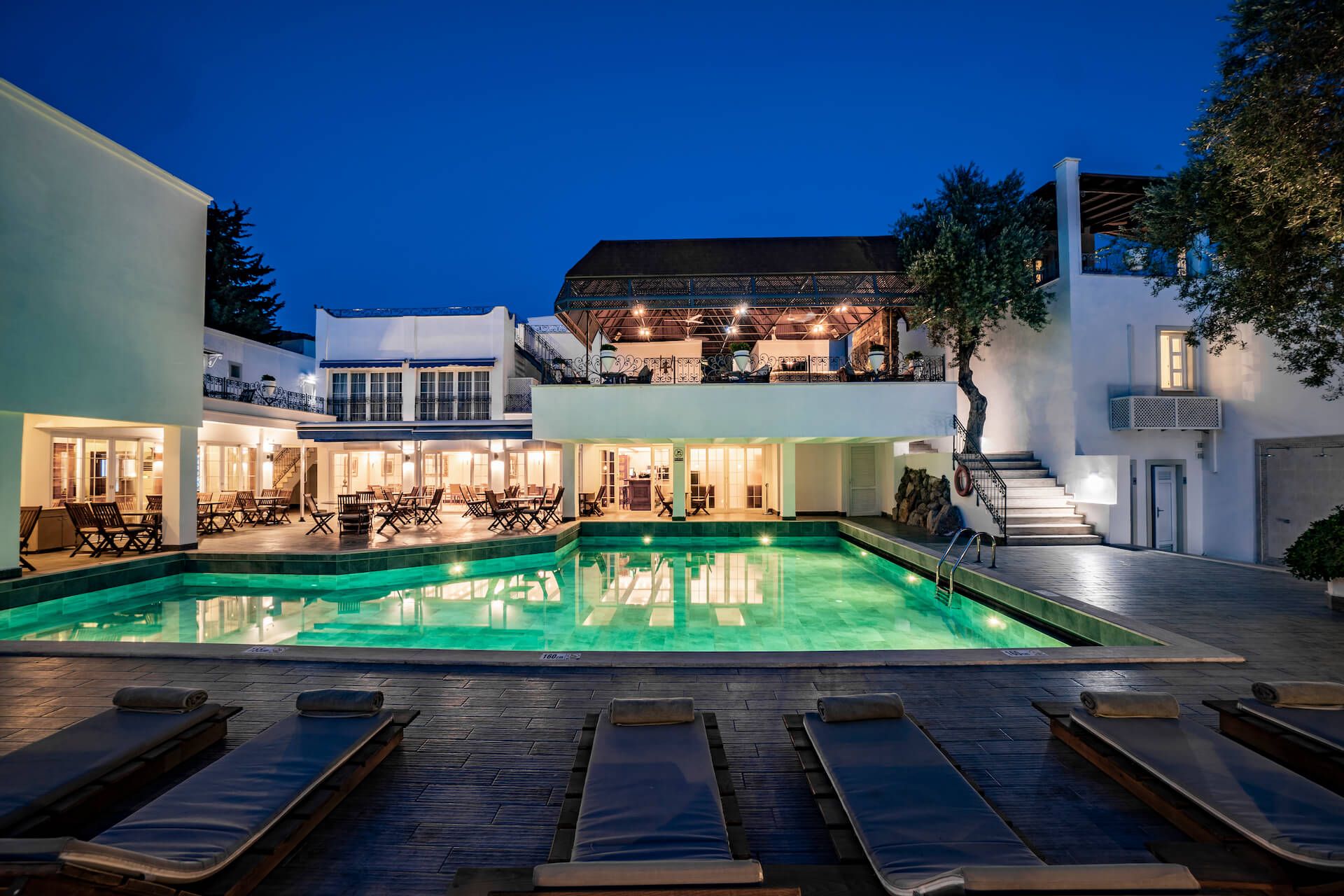 A large swimming pool in front of a hotel at night