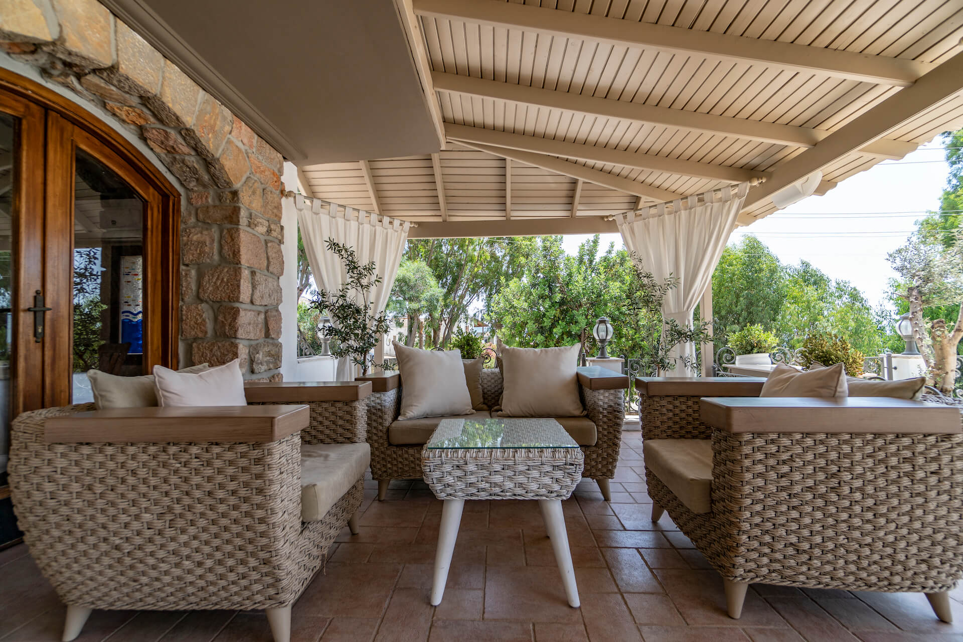 A patio with wicker furniture and a table under a canopy.
