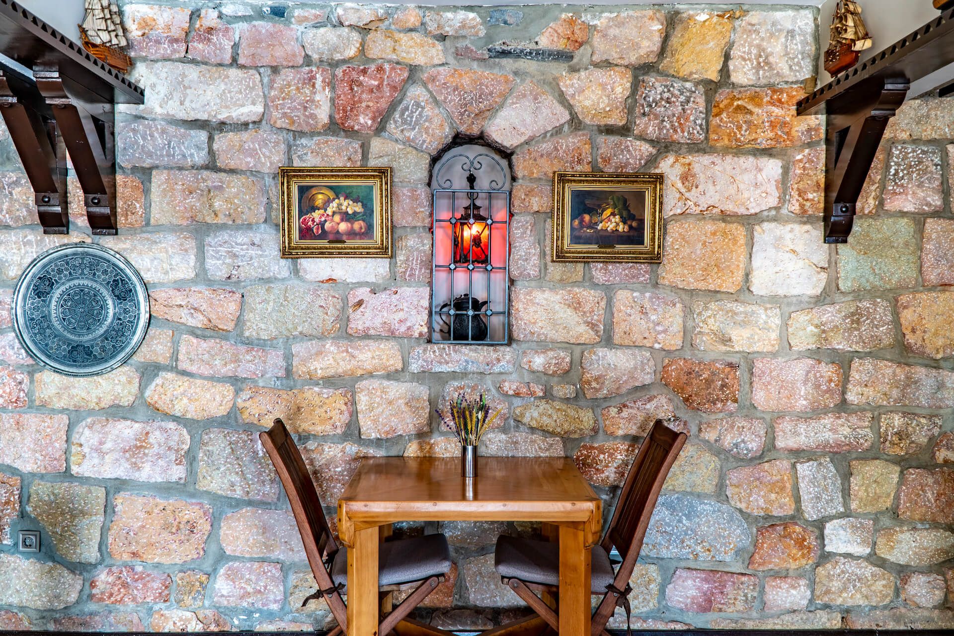 There is a table and chairs in front of a stone wall.