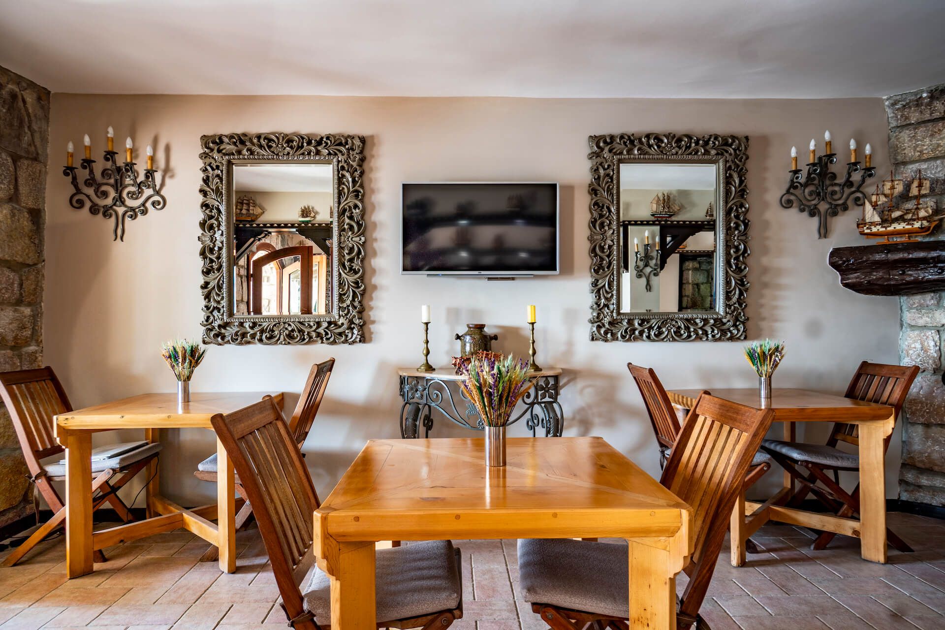 A dining room with wooden tables and chairs and a flat screen tv on the wall.
