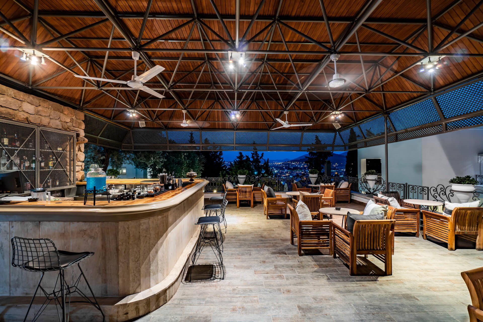A large room with a bar and chairs under a wooden roof.