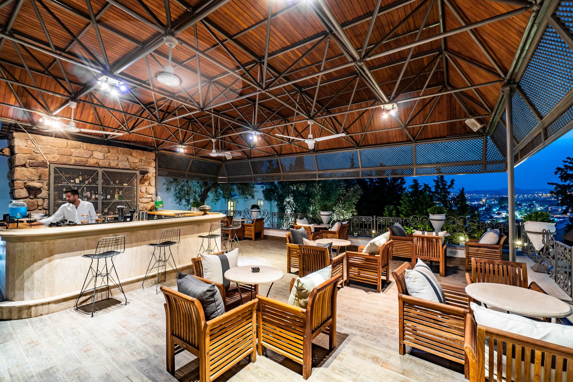 A restaurant with a bar , chairs , tables and a view of the city.