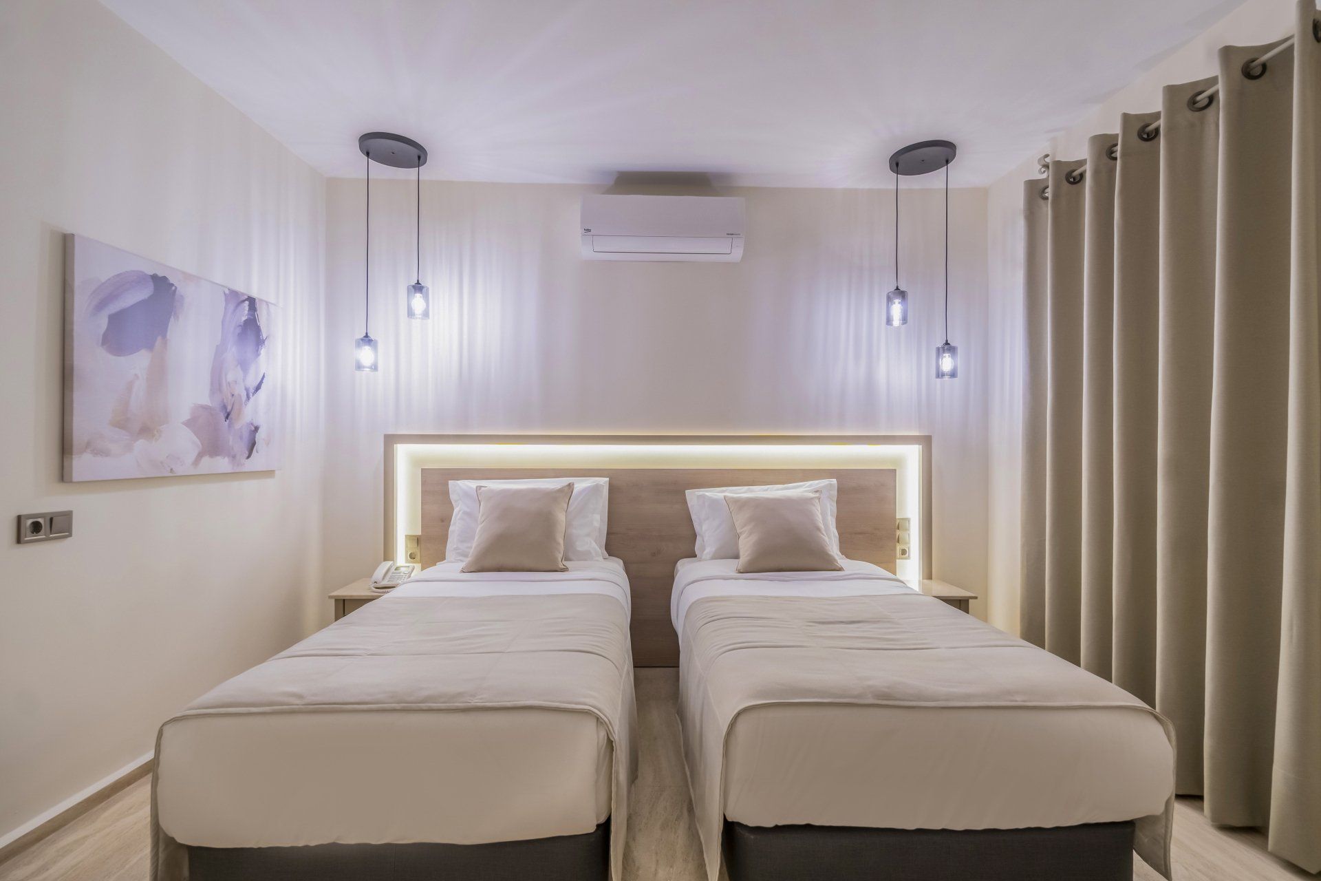 A hotel room with two beds and a painting on the wall.