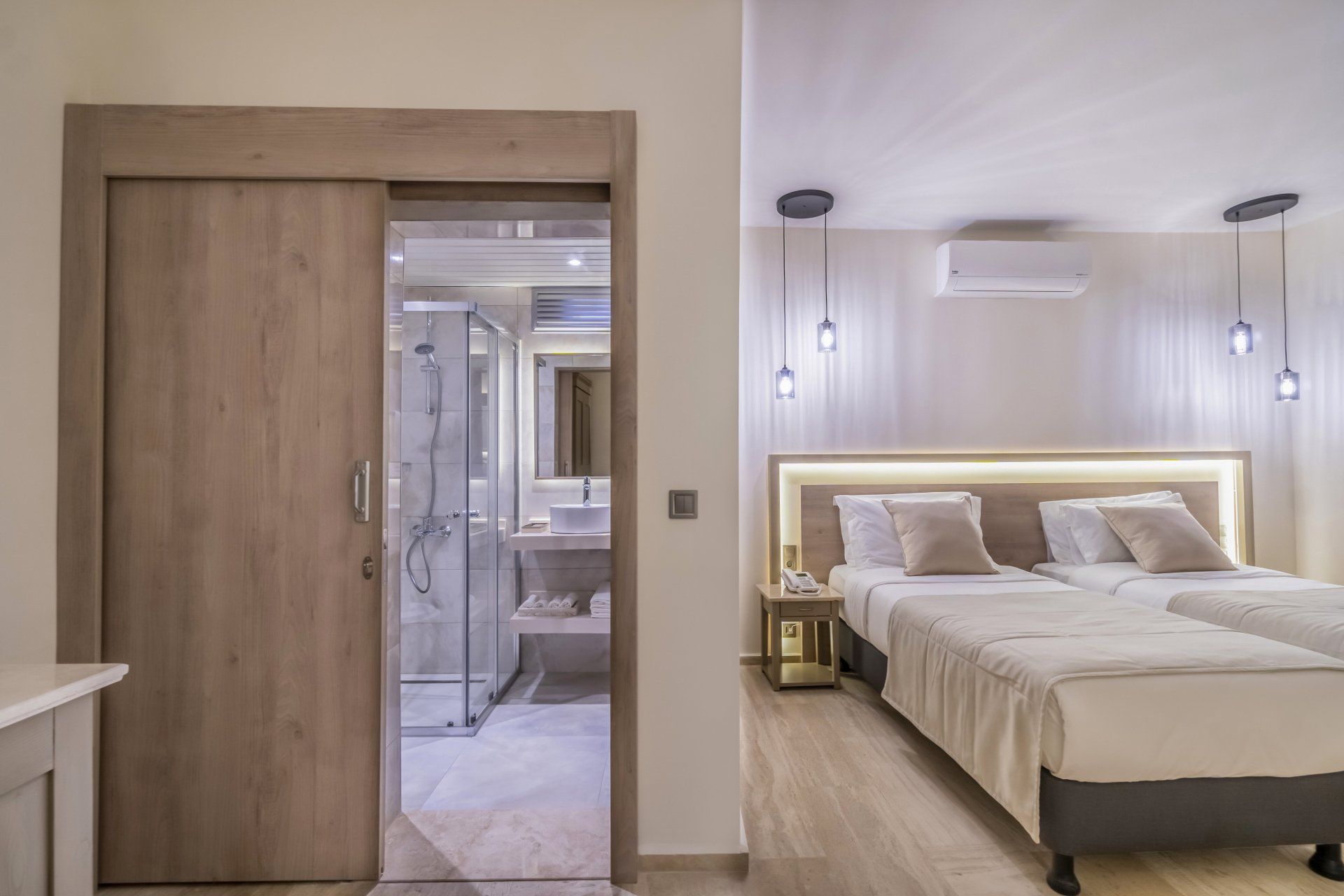 A hotel room with two beds and a sliding door leading to a bathroom.