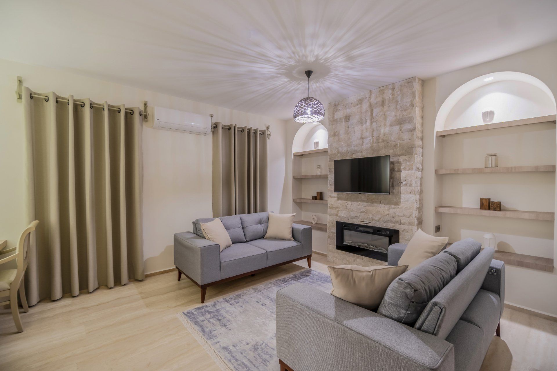A living room with a couch , chair , television and fireplace.