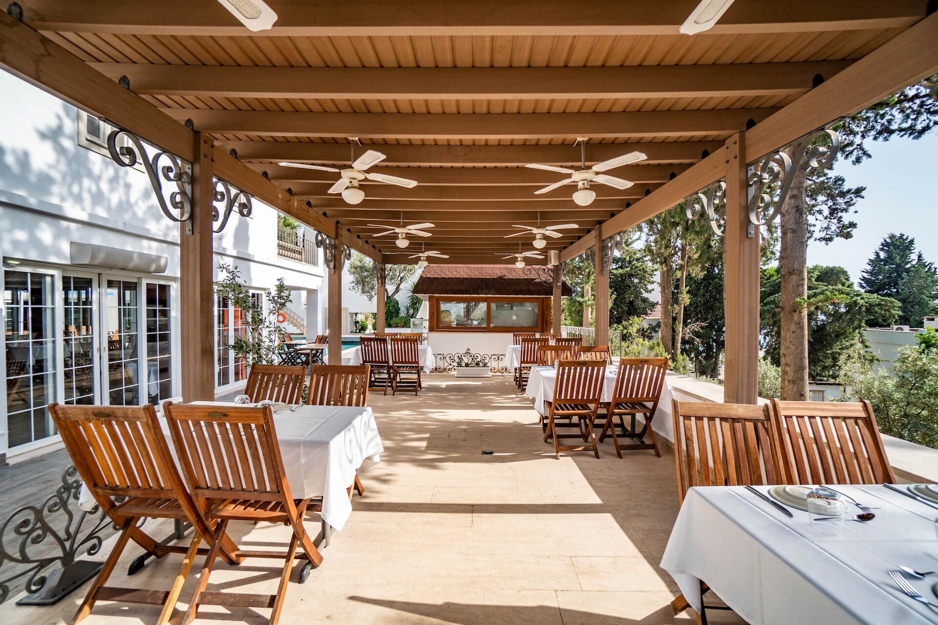 A patio with tables and chairs under a pergola.