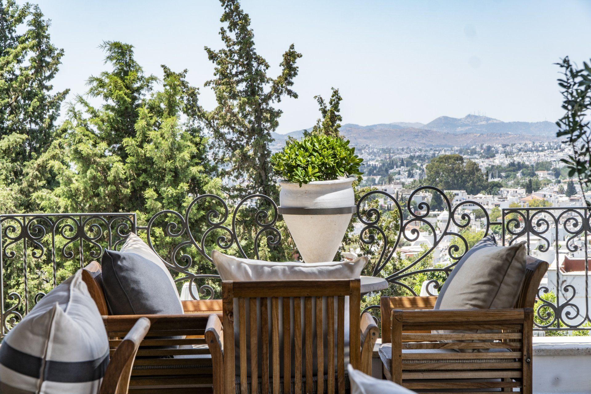 There is a table and chairs on the balcony with a view of the city.