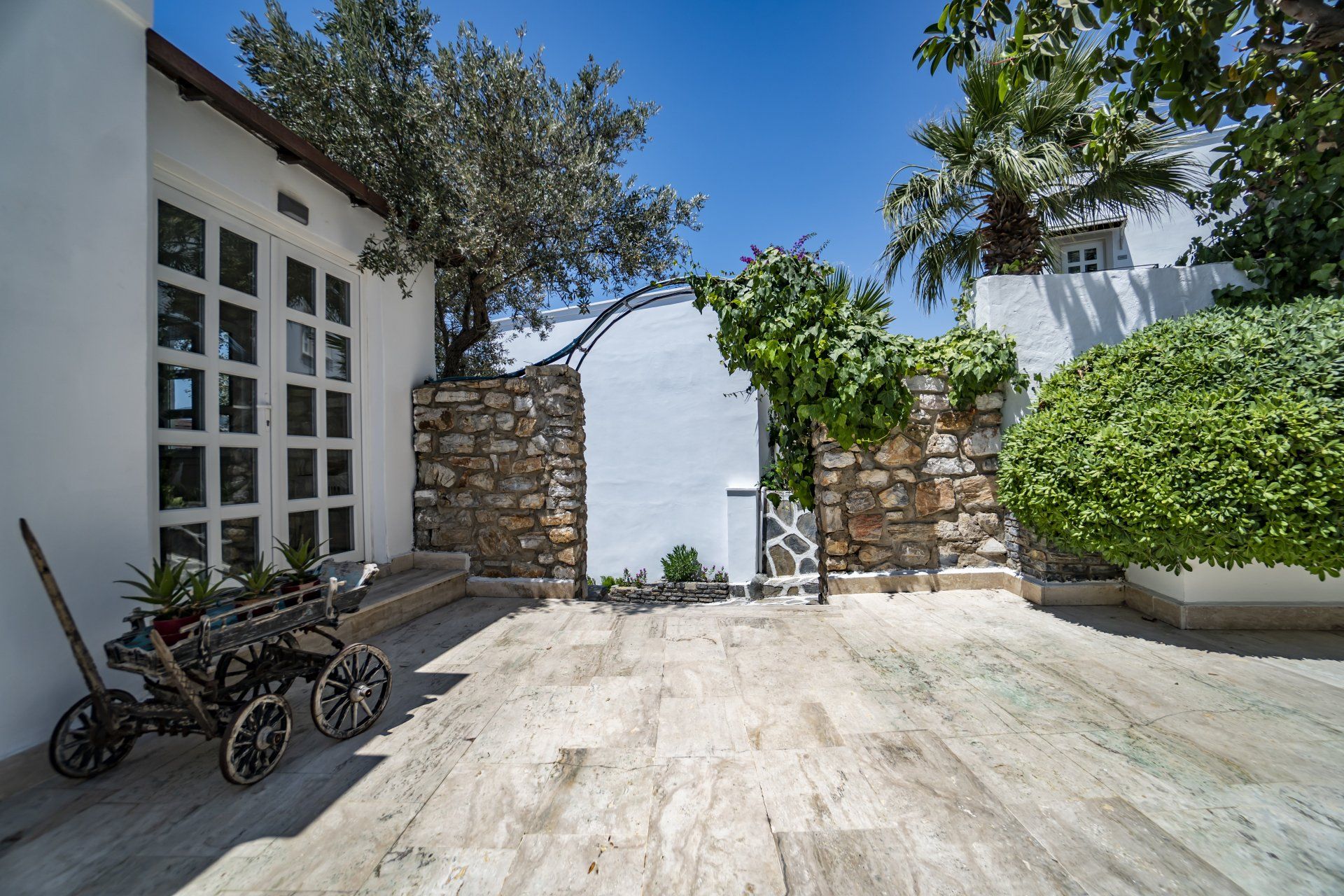 A wooden wagon is parked in front of a white building.