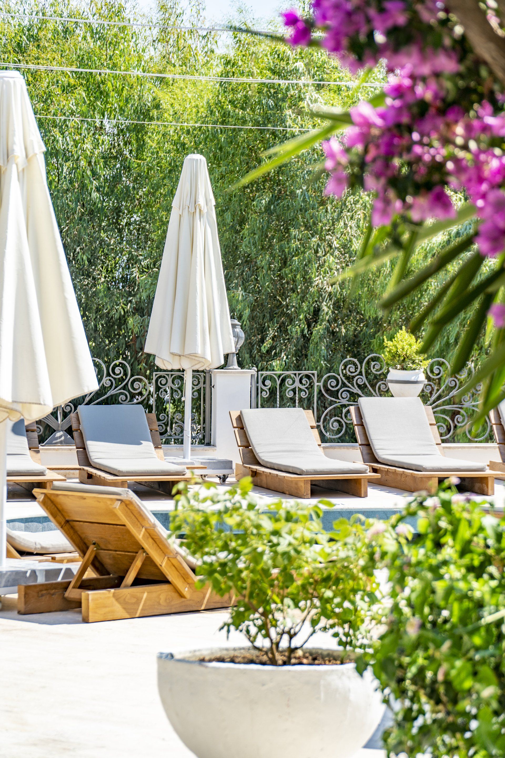 A row of lounge chairs and umbrellas next to a swimming pool.