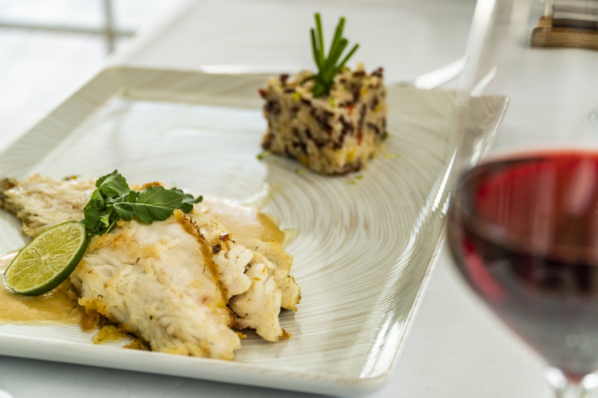 A plate of food and a glass of wine on a table.