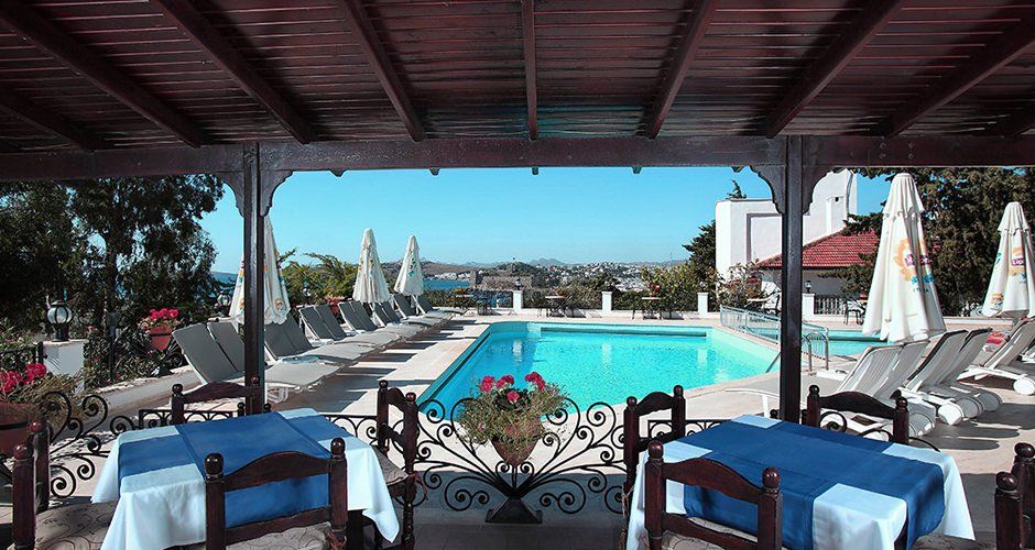 A restaurant with tables and chairs overlooking a swimming pool
