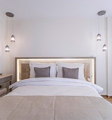 A bedroom with a bed , nightstand , and lamps hanging from the ceiling.