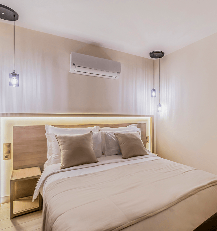 A hotel room with a bed , nightstand , and air conditioner.